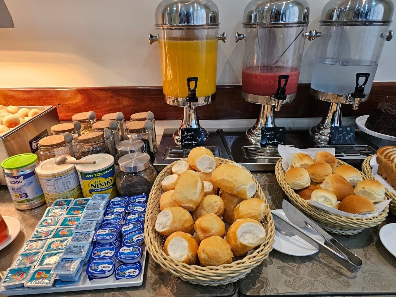A buffet setup with various food items, including bread, pastries, and beverages.