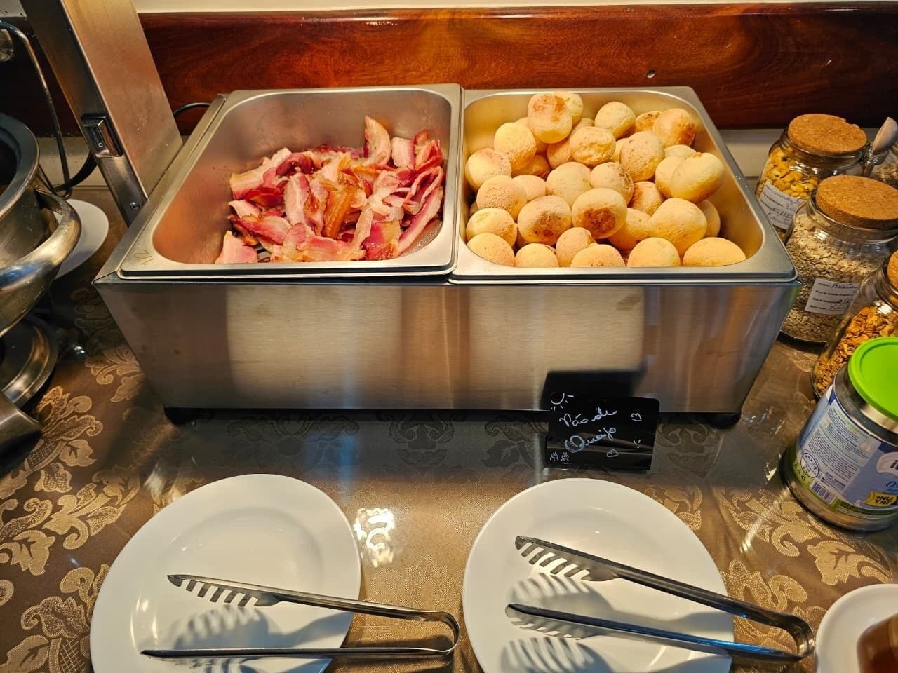 Buffet com duas travessas de comida, uma com bacon e outra com pães.