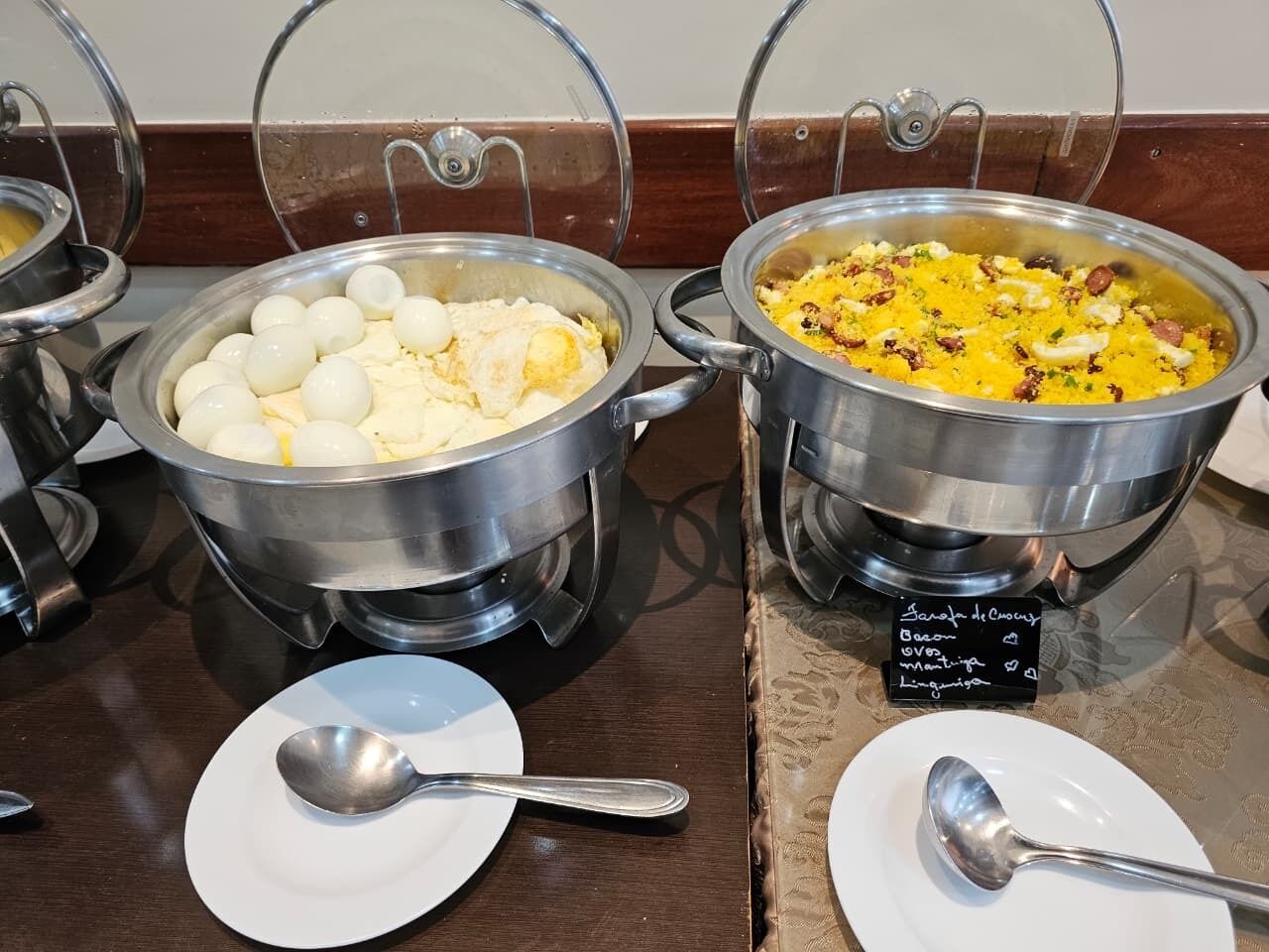 A buffet setup with two large pots of food, one containing boiled eggs and the other with a yellow dish, possibly rice or curry, garnished with herbs.