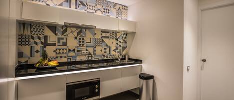 Una cocina moderna con un salpicadero geométrico, electrodomésticos de acero inoxidable y un cubo de basura.