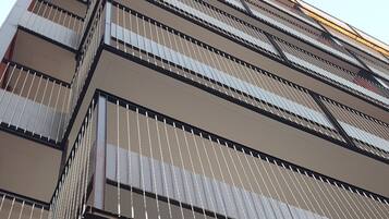 A multi-story building with a modern architectural design, featuring balconies with metal railings and large windows.