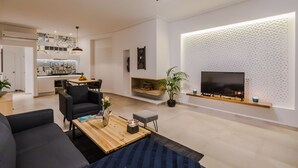 Una sala moderna con chimenea, un televisor de pantalla plana y un comedor con una cocina al fondo.