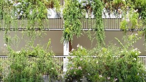Un edificio de varios pisos con balcones cubiertos de follaje y flores.