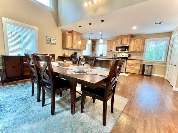 A spacious kitchen with wooden cabinets, a dining table with chairs, and pendant lighting.