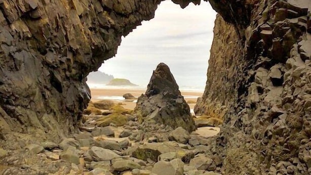 Una playa rocosa con un arco natural que da al mar.