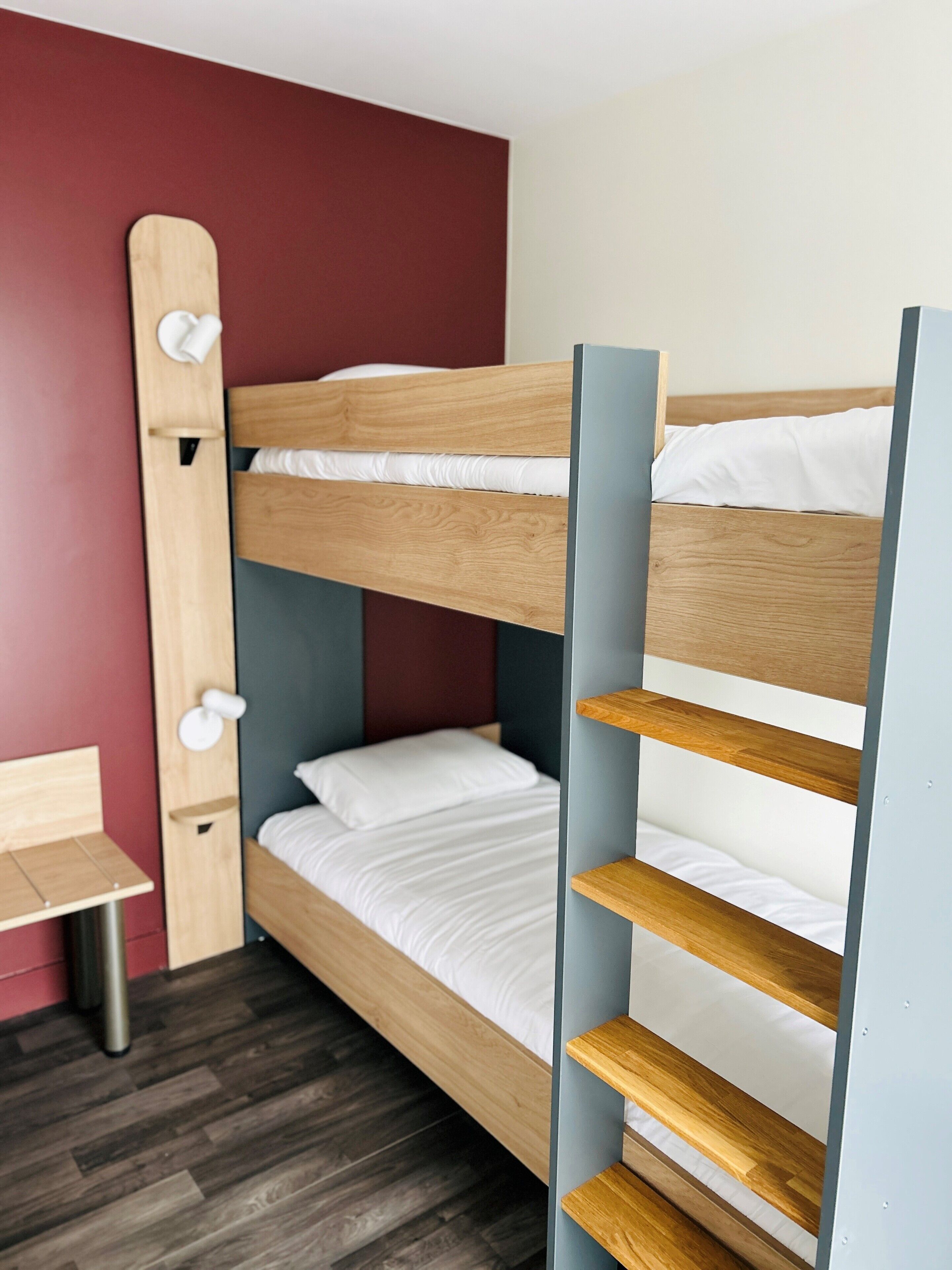 Una cama litera con cabecera de madera y un escritorio con silla.