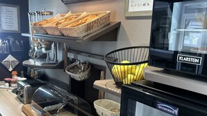 Een ontbijtbuffet met brood, gebak en zuivelproducten.