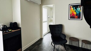 Een moderne woonkamer met een donker houten vloer, een zwarte fauteuil en een koffieapparaat op een houten tafel.