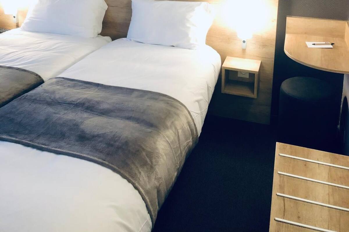 Een hotelkamer met een groot bed, twee nachtkastjes, een klein rond tafeltje en een stoel.