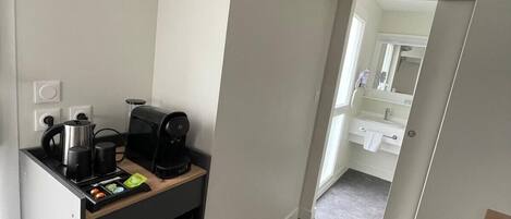 A compact kitchen with a coffee maker, kettle, and toaster on a countertop.
