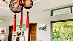 Un intérieur moderne avec un comptoir d’accueil en bois, une grande fenêtre donnant sur un espace verdoyant et un ventilateur de plafond.