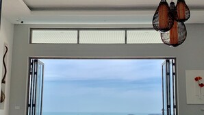 Un salon moderne doté d’une grande porte-fenêtre coulissante donnant sur un balcon avec vue sur la mer.