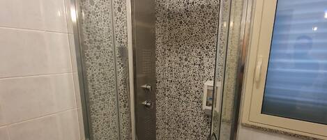 Un baño con ducha de vidrio, inodoro y lavamanos.
