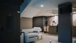 A modern hotel lobby with a reception desk, seating area, and a staircase. - Hotel Casale dei Greci (Biancavilla)