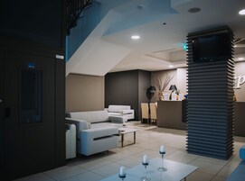 Un moderno vestíbulo de hotel con recepción, zona de estar y escalera.