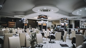 A modern restaurant with round tables, white chairs, and a central floral arrangement. - Hotel Casale dei Greci (Biancavilla)