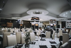 Un restaurante moderno con mesas redondas, sillas blancas y un arreglo floral central.