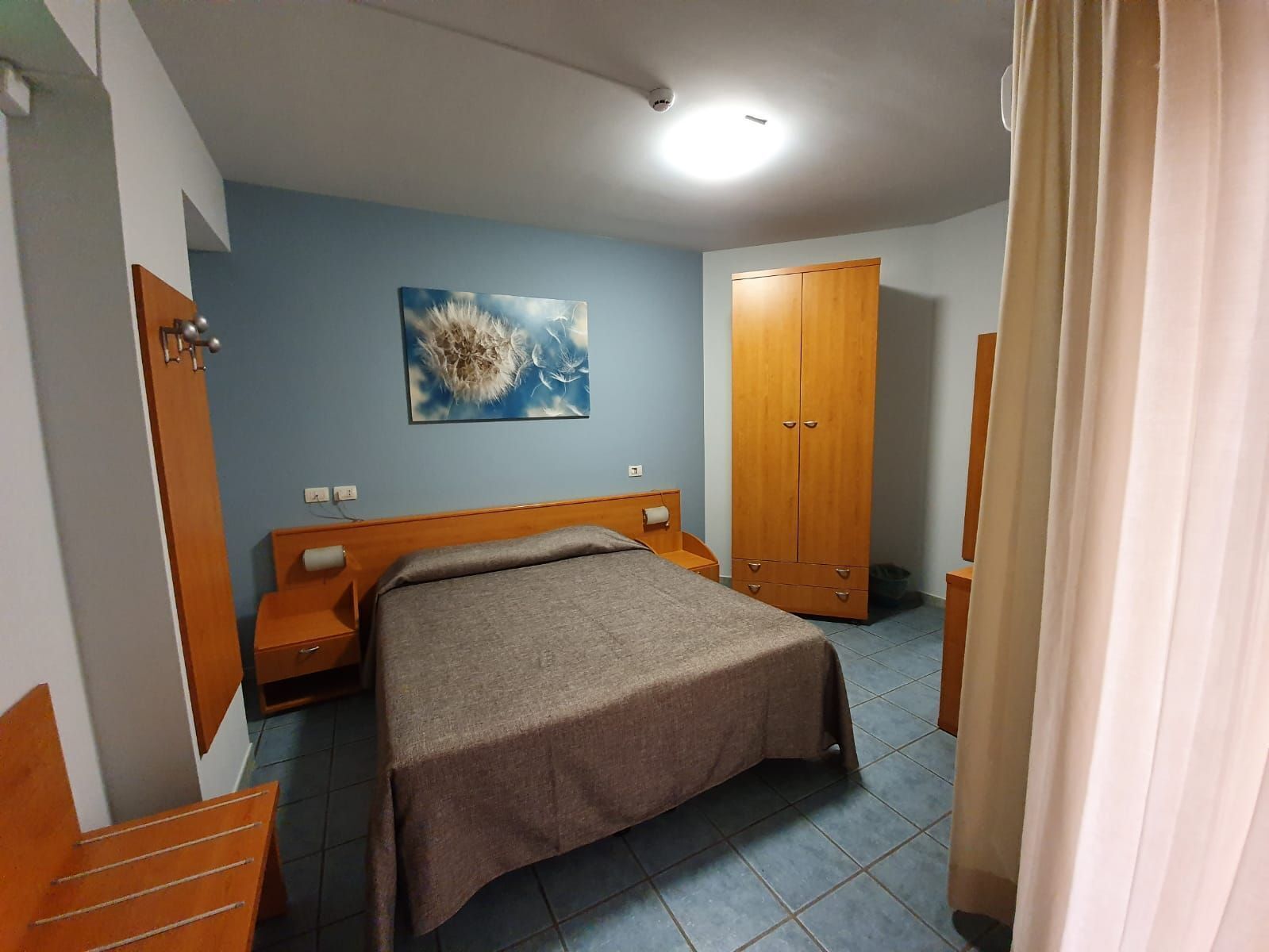 Une chambre à coucher avec un lit, une armoire en bois et un tableau accroché au mur.