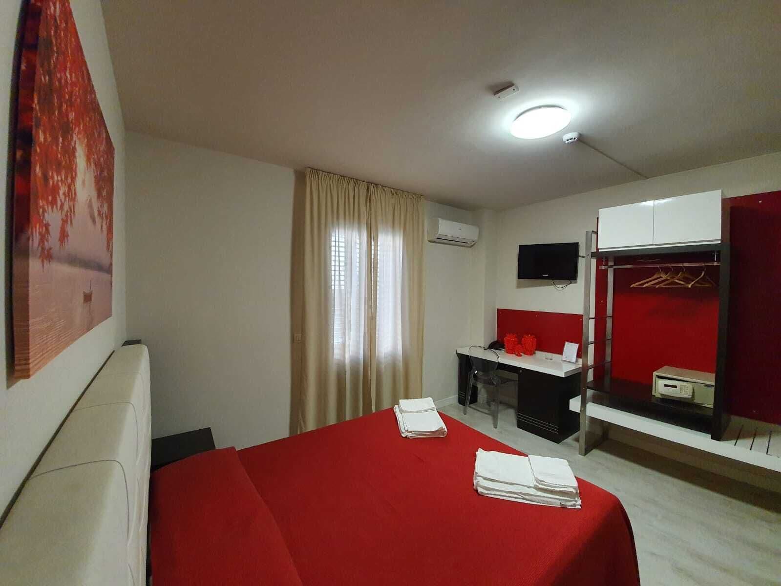 Una habitación de hotel con cama, escritorio, televisor y armario.