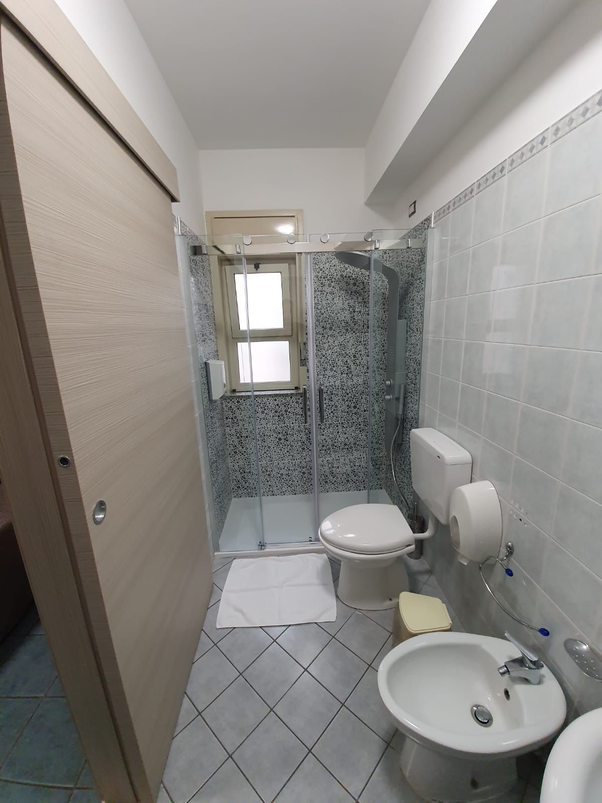 Un baño pequeño con ducha, inodoro y lavamanos.