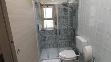 A compact bathroom with a shower, toilet, and sink.