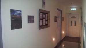A hallway with a door, a bulletin board, and two framed pictures on the wall. - Appartment Graz Zentrum (Graz)