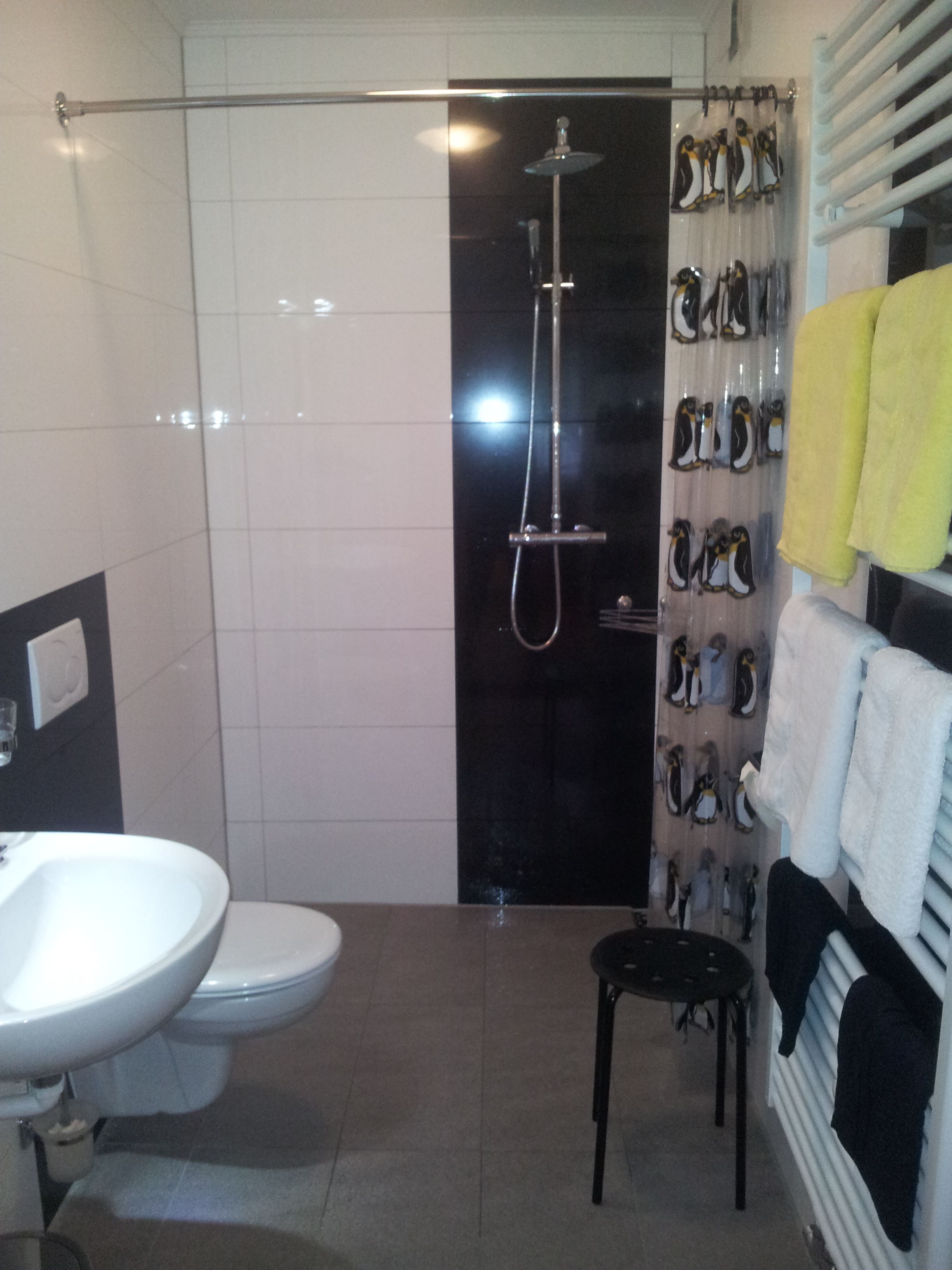 A bathroom with a toilet, sink, shower, and a towel rack with multiple towels.