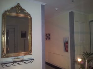 A hallway with a large ornate mirror, a small shelf with a bowl, and a fire extinguisher on the wall. - Appartment Graz Zentrum (Graz)