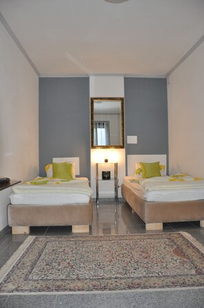 Une chambre d’hôtel avec deux lits, un grand miroir, une table de chevet et un tapis à motifs.