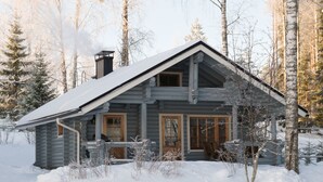 Eine Blockhütte mit steiler Satteldachkonstruktion, Holzfassade und Schornstein.
