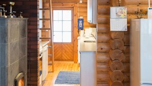 Ein rustikaler Blockhaushof mit Kamin, Holzwänden, einer Küchenzeile und einer Holztreppe.