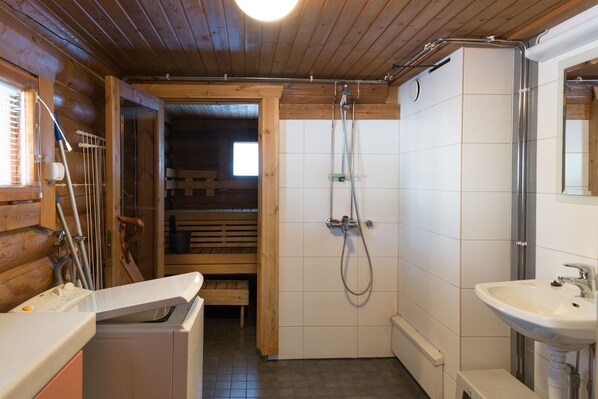 Een badkamer met houten inrichting, een wit wastafelmeubel en een douchegedeelte.