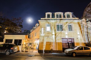 Um edifício com estilo arquitetônico clássico, destacando uma entrada imponente com portão e uma grande janela.