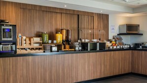 Una recepción moderna con una máquina de café, dispensadores de condimentos y un microondas.
