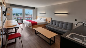 Una habitación de hotel moderna con cama, sofá, escritorio y kitchenette.
