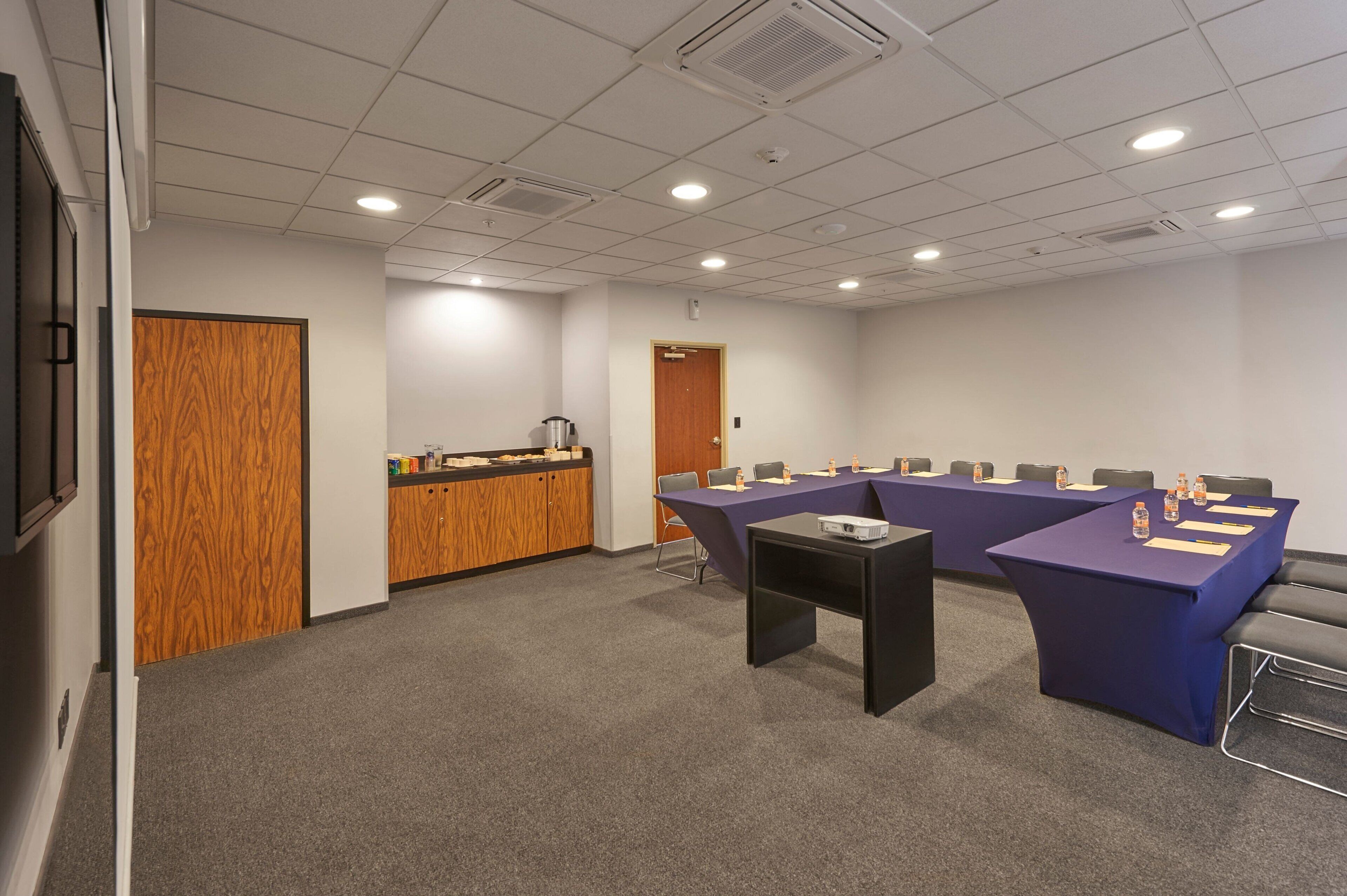 A conference room with a long table, a reception desk, and a door.