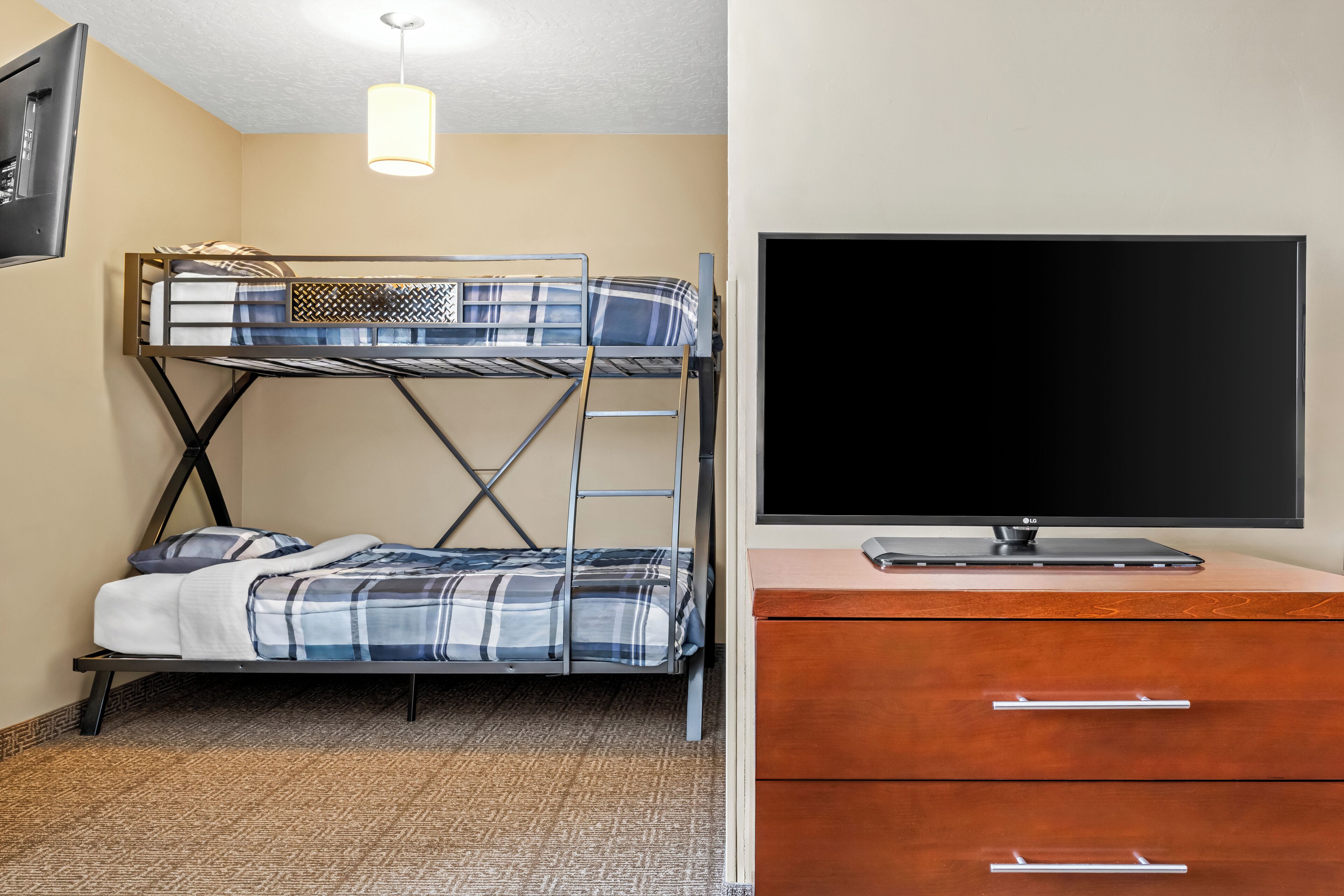 A bunk bed with a TV on a dresser, a lamp, and a patterned rug.