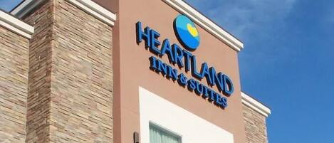 Hotellin kyltti, jossa on nimi ”Heartland Inn & Suites” ja logo.