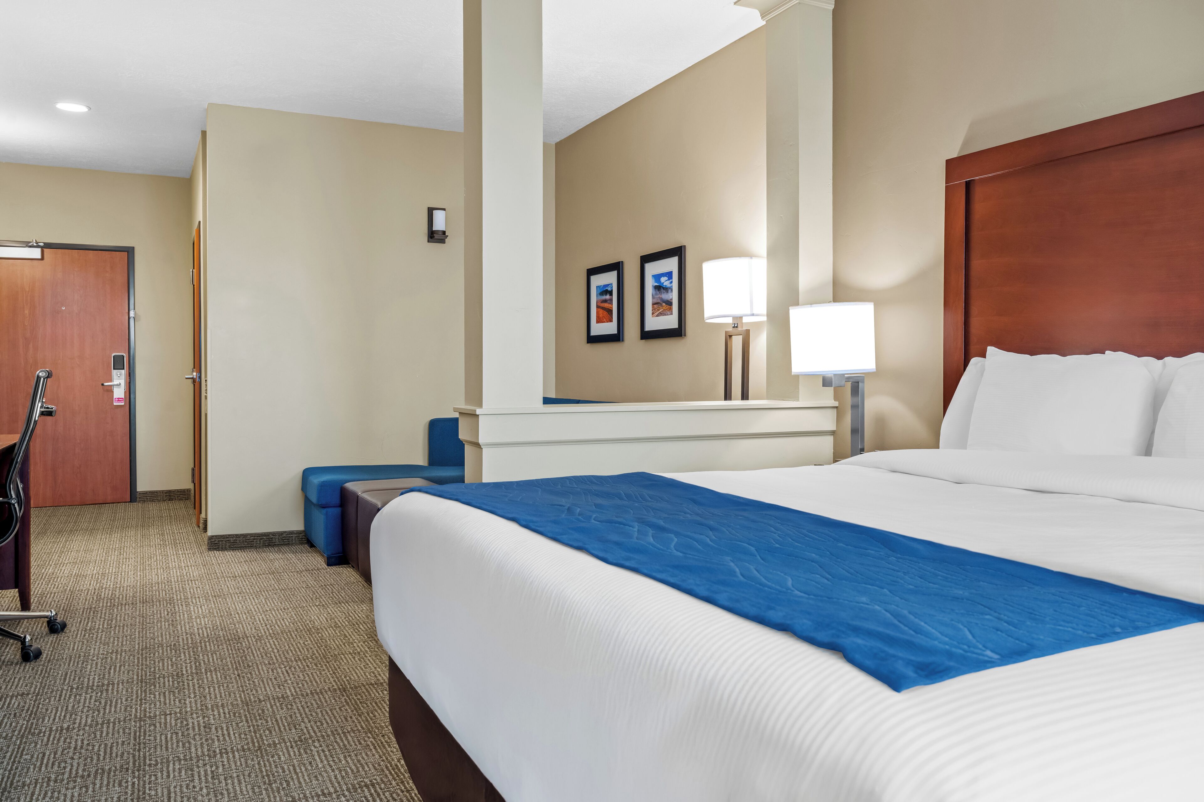 A hotel room with a large bed, a desk, and a chair.