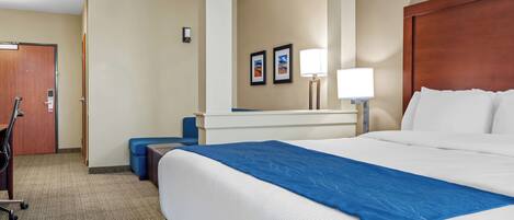A hotel room with a large bed, a desk, and a chair.