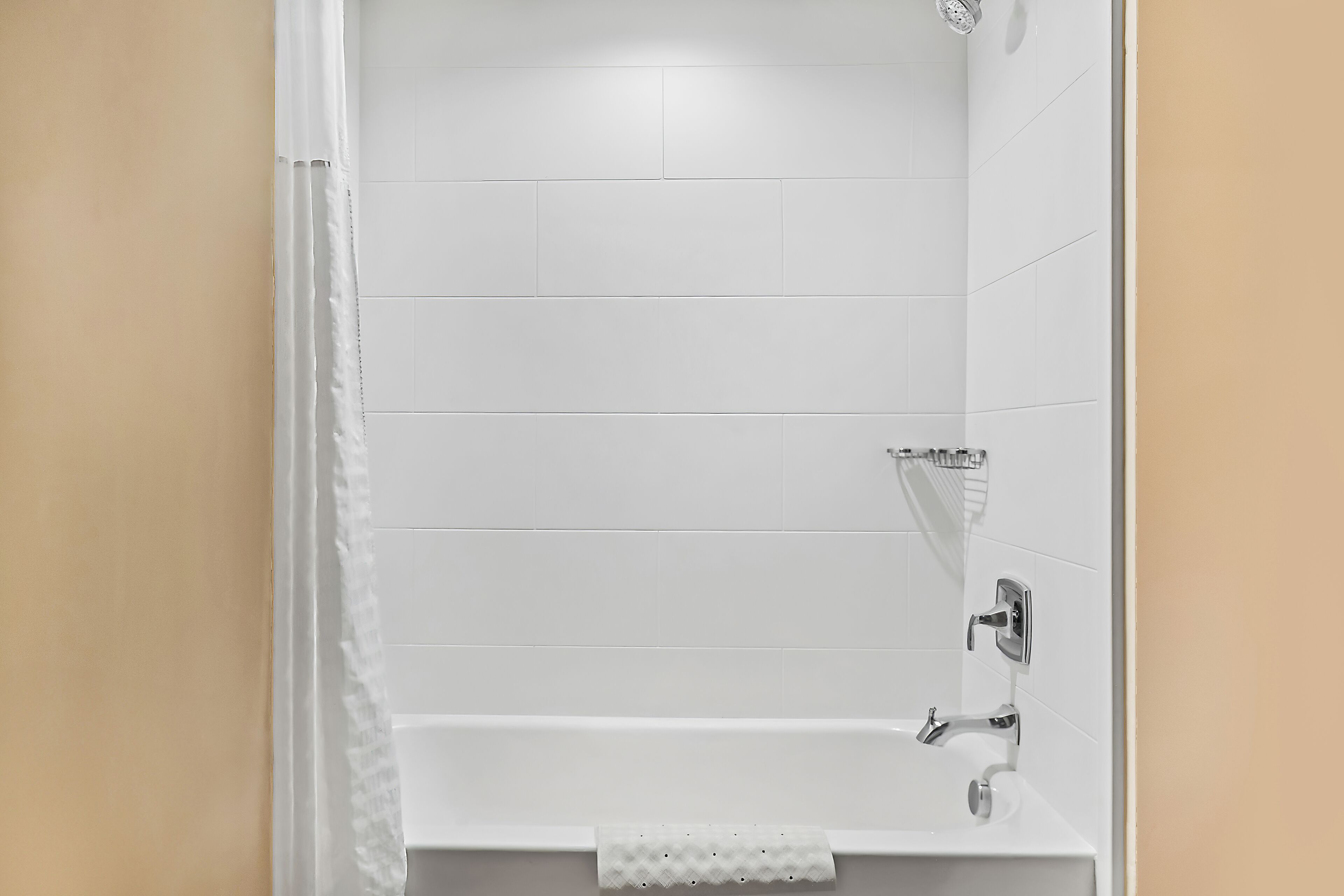 A bathroom with white tiles, a shower, and a sink with a towel rack.