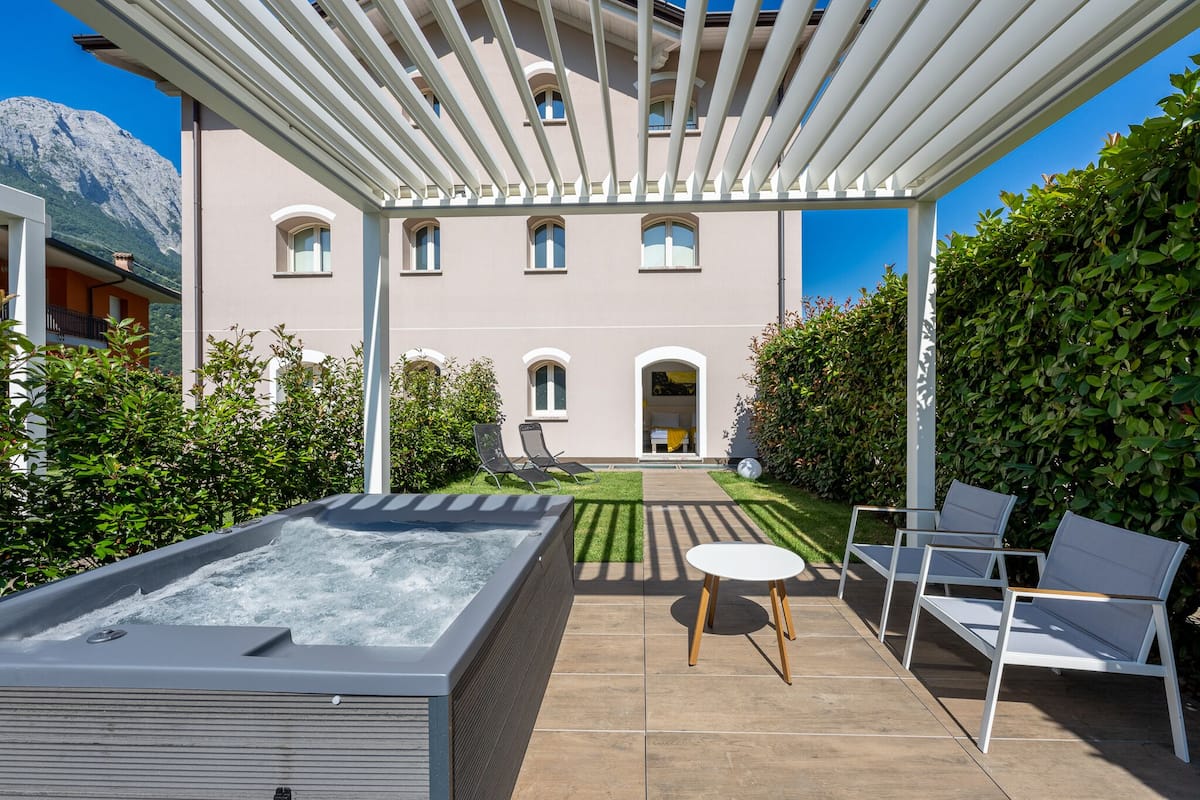 Un espace bien-être comprenant un jacuzzi, des sièges extérieurs et une vue sur un bâtiment doté de nombreuses fenêtres.