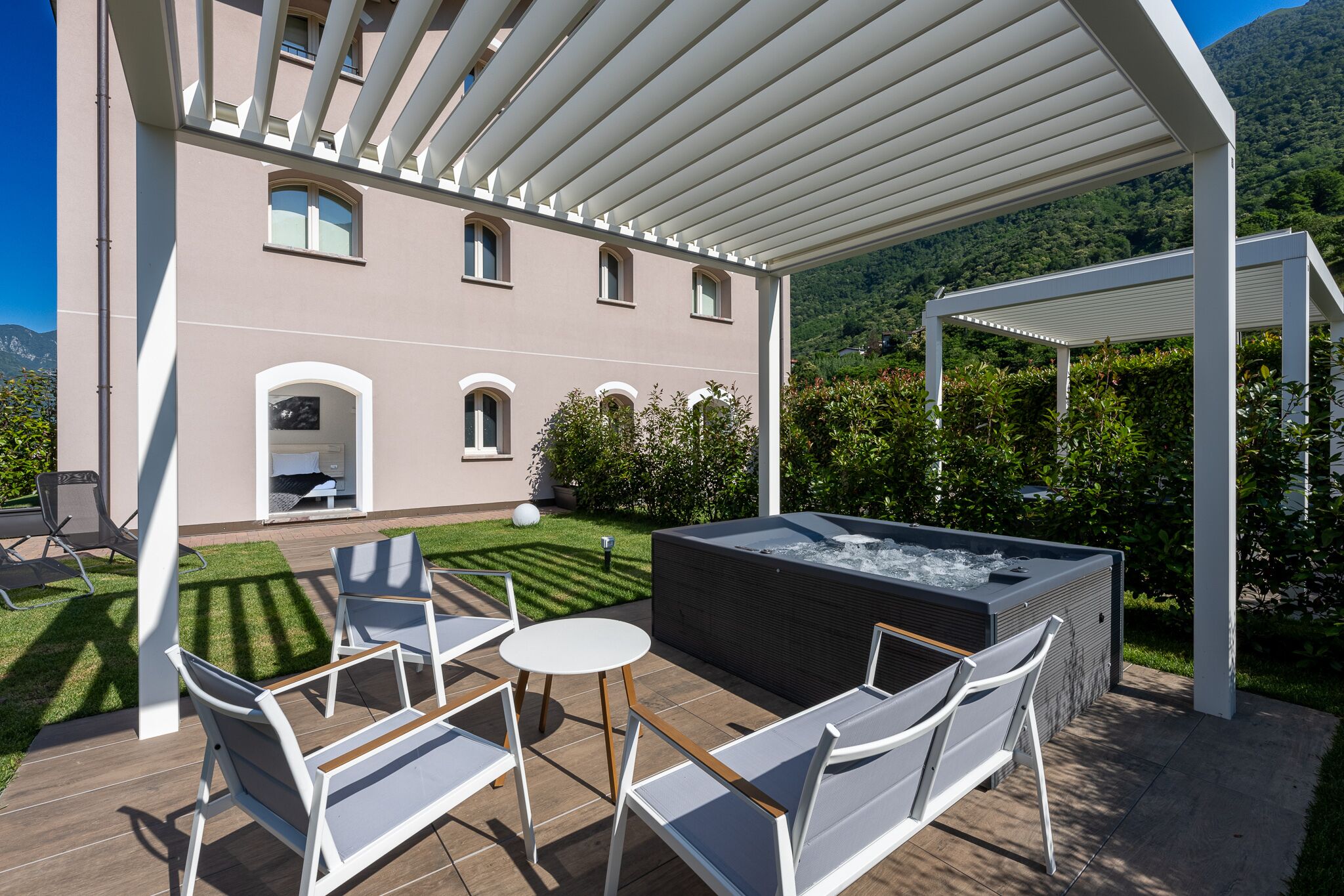 Une terrasse extérieure moderne dotée d’un jacuzzi, de chaises longues et d’une pergola.