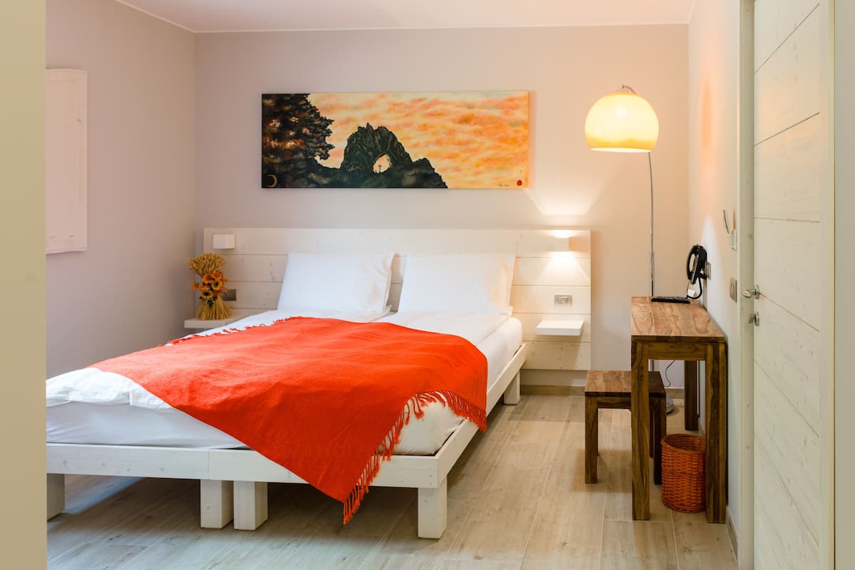 Une chambre à coucher bien rangée, avec un lit, des tables de chevet, une lampe et un tableau au mur.