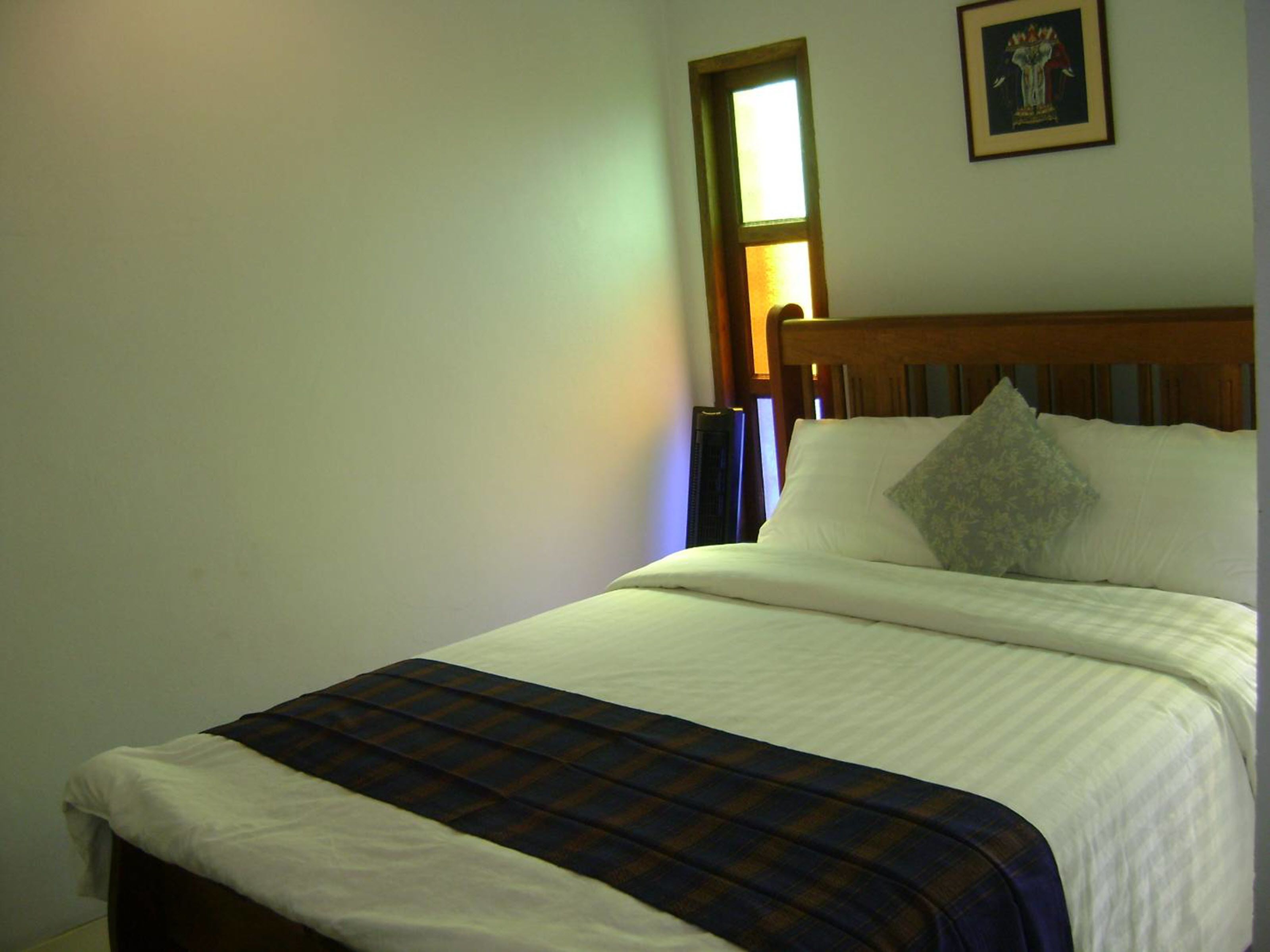 A bedroom with a bed, a window, and a framed picture on the wall.
