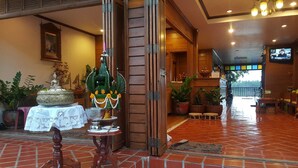 Un intérieur traditionnel avec une porte en bois, une statue de Bouddha et une grande fontaine représentant Bouddha.