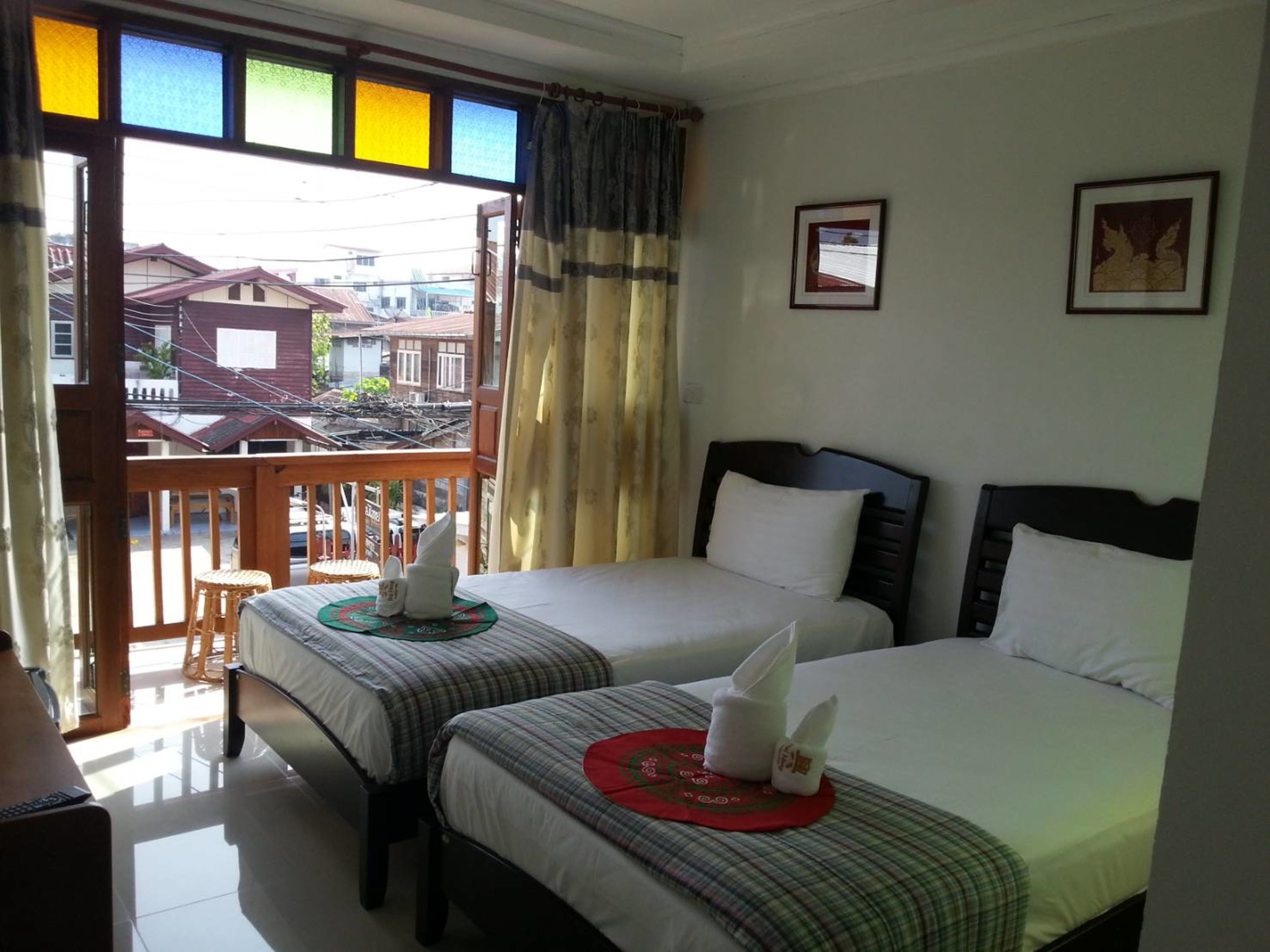 Habitación de hotel con dos camas, un balcón y vistas a edificios.