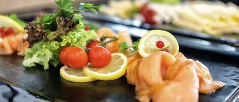 A variety of food items on a tray, including salmon, tomatoes, and lemon slices.