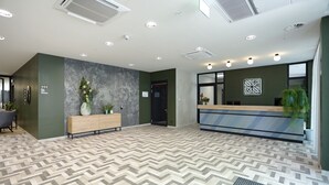Un espace d’accueil d’hôtel au design moderne, comprenant un comptoir d’accueil, un banc et un sol à motifs.
