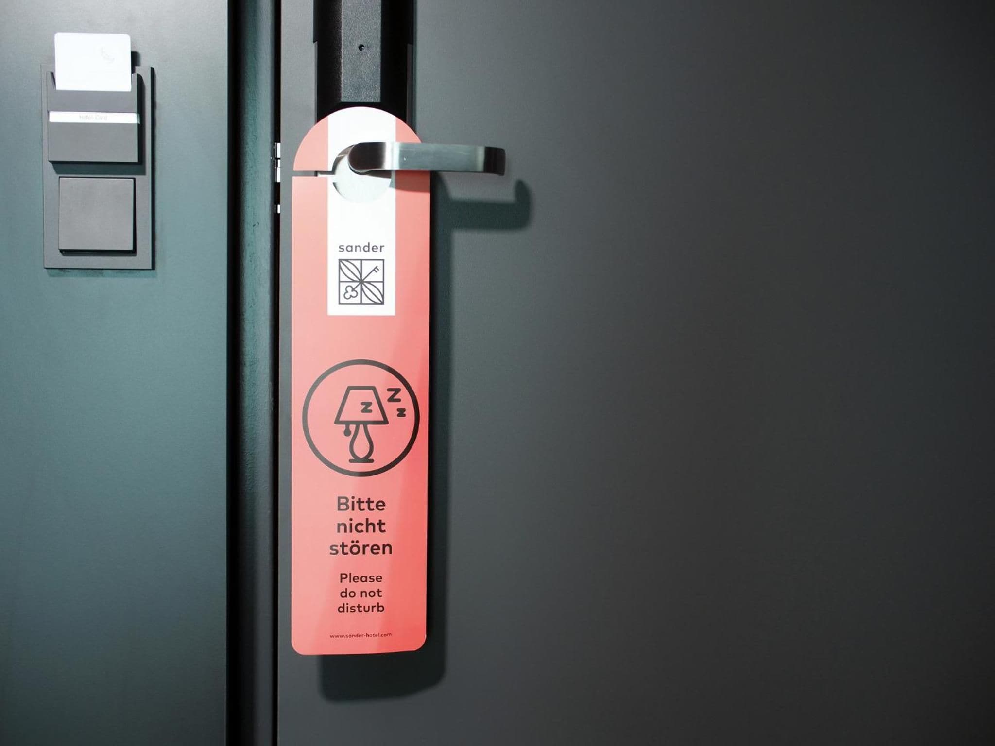 A hotel room door with a keycard slot, a keycard, and a sign requesting guests not to disturb.